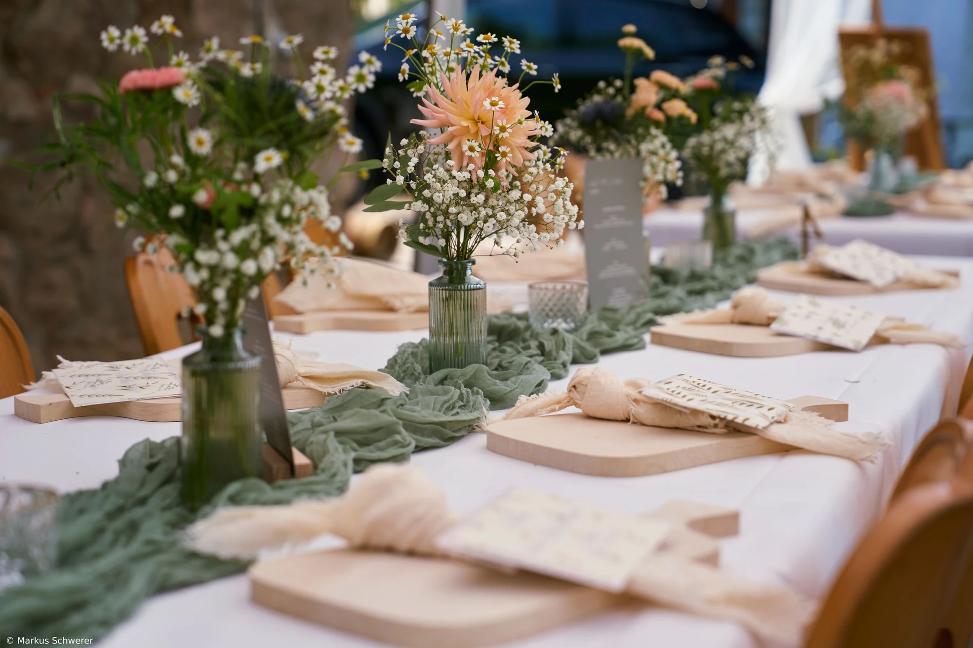 Gedeckte Tafel mit Blumen, Gläsern und Holzbrettern in Müllers Mühle