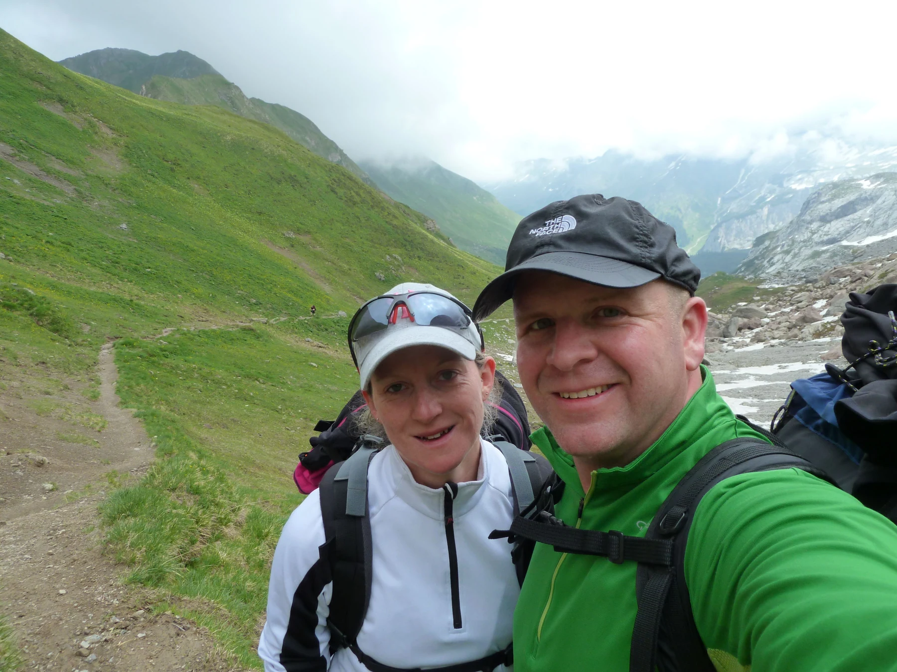 Anja und Rainer mit Rucksäcken am Lünersee vor steilen grünen Berghängen